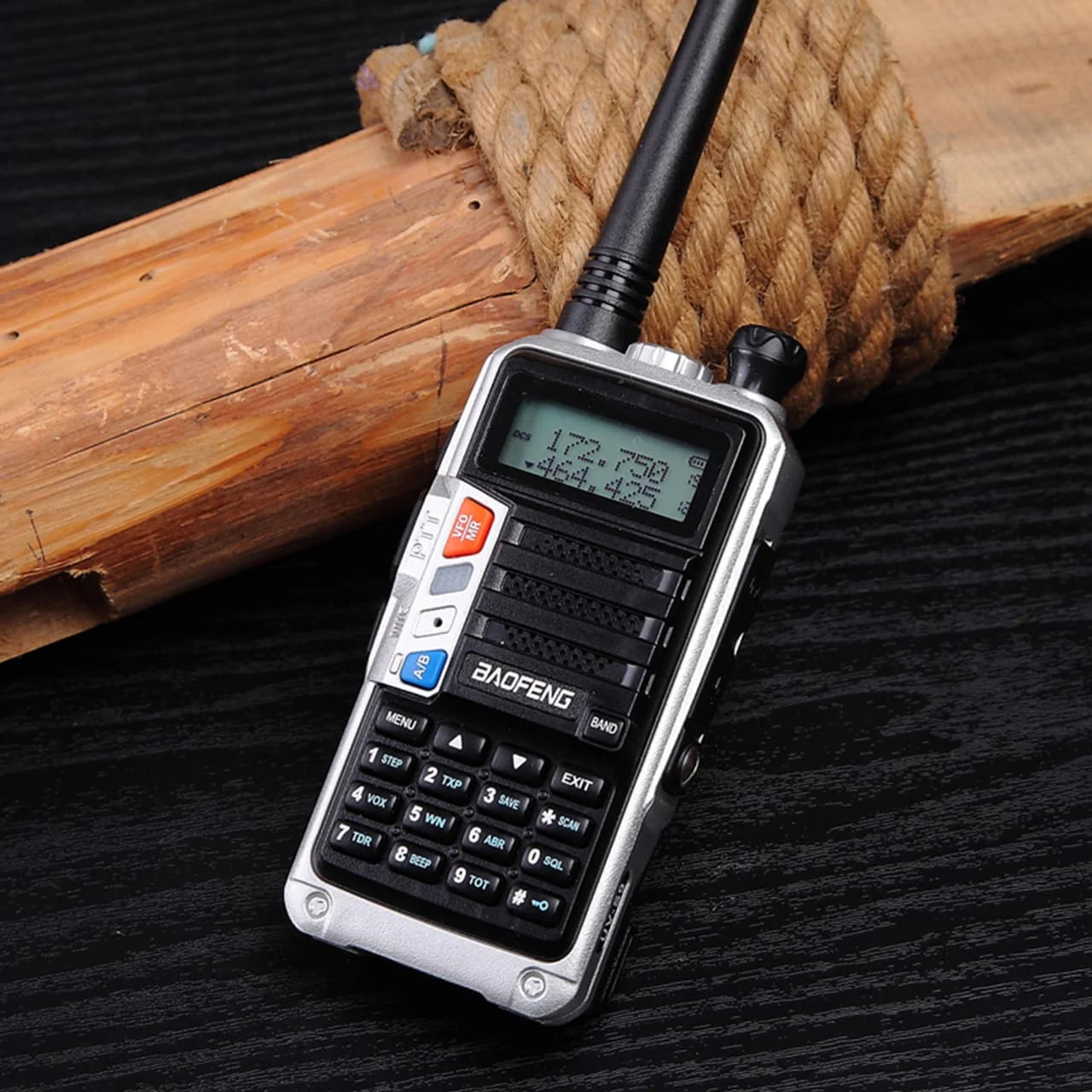 Robustes silbernes Baofeng UV-S9 Tri-Band Funkgerät auf einer rustikalen Holzoberfläche, zeigt das Display und die Tastatur.