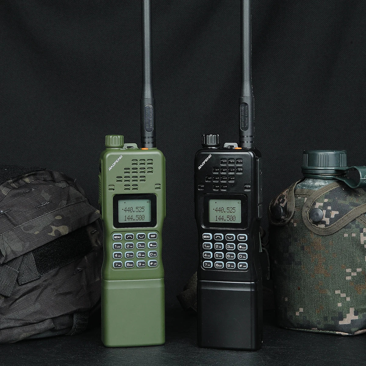 Zwei Baofeng AR-152 Funkgeräte in Grün und Schwarz, mit militärischer Ausrüstung wie Rucksack und Trinkflasche, betonen die militärische Einsatztauglichkeit.