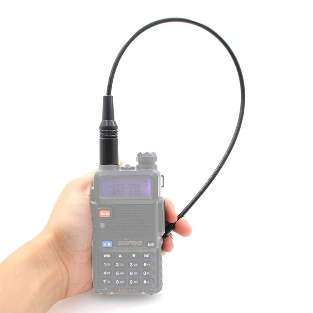 Ein Baofeng UV-5R Funkgerät, an das die flexible NA-771 Antenne angeschlossen ist, wird von einer Hand gehalten. Die Antenne ist nach oben gebogen.